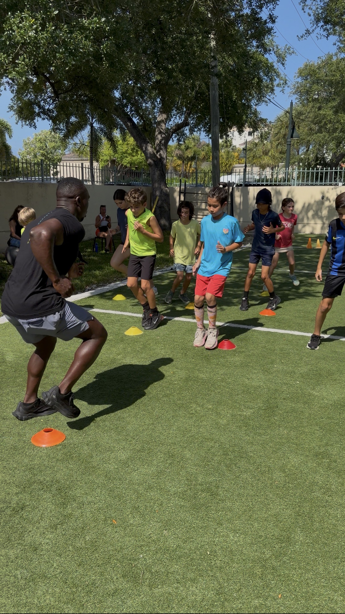 Coach leading kids through an outdoor turf cone drill at Boca Youth Fit